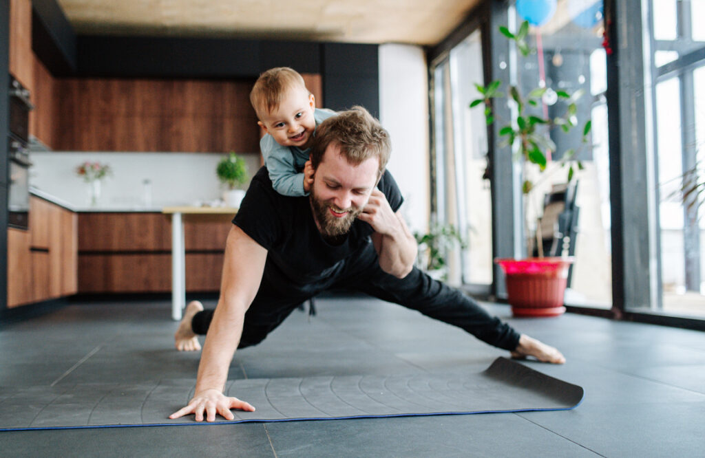 A man doing a one man push-up with a child on his back